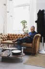 Фрилансер, сидящий на диване и пользующийся цифровым планшетом — стоковое фото