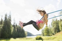 Side view of girl on swing, focus on foreground — Stock Photo
