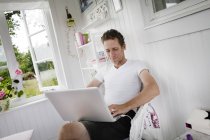 Чоловік середнього віку використовує ноутбук вдома — стокове фото