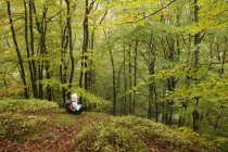 Femme adulte moyenne assise dans la forêt — Photo de stock