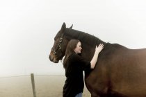 Mittelerwachsene Frau mit Pferd auf Feldweg im Nebel — Stockfoto