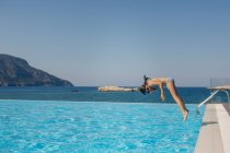 Seitenansicht eines jungen Mädchens, das im Sommer in einen Pool springt — Stockfoto