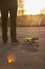 Uomo in piedi con skateboard su strada al tramonto — Foto stock