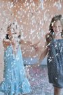 Two young girls playing in confetti, selective focus — Stock Photo