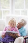 Grand-mère et petite-fille utilisant une tablette numérique, se concentrer sur le premier plan — Photo de stock