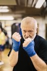 Hombre mayor con los puños levantados en el entrenamiento de boxeo, se centran en primer plano - foto de stock