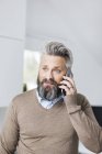 Man in brown sweater talking on cell phone — Stock Photo