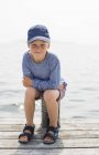 Niño sentado en el poste en embarcadero, enfoque selectivo - foto de stock