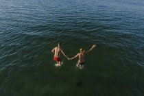 Hombre y mujer saltando al mar - foto de stock