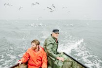 Uomini in impermeabili pesca in mare, focus selettivo — Foto stock