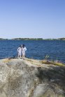 Boys standing on rock in bay, focus on foreground — Stock Photo