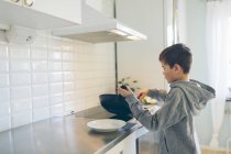 Молодий хлопчик готує на домашній кухні — стокове фото