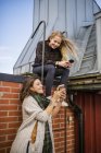 Дві молоді жінки використовують телефони на даху, вибірковий фокус — стокове фото