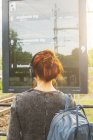 Rear view of woman in headphones by train sign — Stock Photo