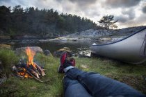 Personal perspective of man lying by campfire on riverbank — Stock Photo