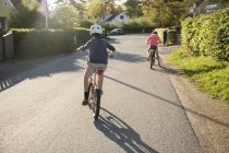 Visão traseira de crianças pedalando em dia ensolarado — Fotografia de Stock