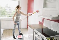 Donna con capelli castani pittura parete in cucina — Foto stock
