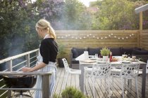 Side view of mature woman cooking on patio — Stock Photo