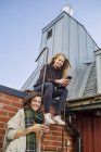 Duas jovens mulheres usando telefones inteligentes no telhado — Fotografia de Stock