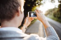 Man photographing road at sunset, selective focus — Stock Photo