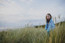 Junges Mädchen steht im langen Gras — Stockfoto