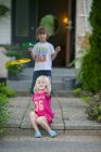 Siblings playing in front of house, selective focus — Stock Photo