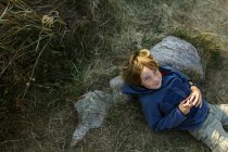 Giovane ragazzo sdraiato contro la roccia — Foto stock