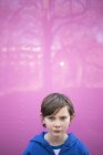 Porträt eines Jungen vor rosa Wand, der in die Kamera blickt — Stockfoto