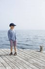 Мальчик стоит на пристани с руками в карманах — стоковое фото