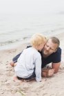Son kissing father on chick, focus on foreground — Stock Photo