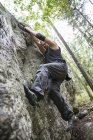 Deportista haciendo bouldering en el bosque, enfoque selectivo - foto de stock