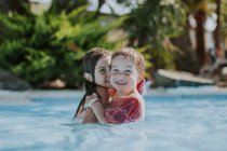 Zwei kleine Kinder schwimmen im Pool und schauen in die Kamera — Stockfoto