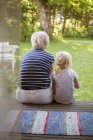 Rear view of woman sitting with girl on porch, differential focus — Stock Photo