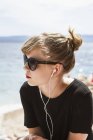 Portrait of girl with earphones at beach, focus on foreground — Stock Photo