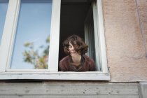 Vista basso angolo di giovane donna appoggiata alla finestra — Foto stock