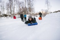 Amigos con toboganes divirtiéndose en invierno - foto de stock