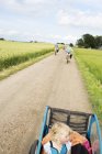 Family cycling at field, focus on foreground — Stock Photo