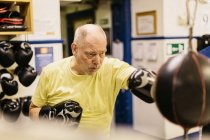 Senior man training with punching bag — Stock Photo