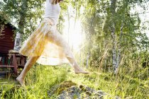 Junge Frau springt in Hinterhof in Gras — Stockfoto