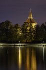 Освещённое здание, отраженное в озере — стоковое фото