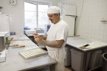 Chef usando el teléfono inteligente en la cocina comercial - foto de stock