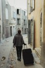Jeune femme marchant avec des bagages dans la vieille ville — Photo de stock