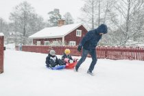 Hombre tirando de los niños en trineo en invierno, se centran en primer plano - foto de stock