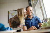 Woman kissing man on cheek, focus on foreground — Stock Photo