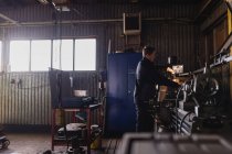 Молодой человек работает в мастерской, дифференциальный фокус — стоковое фото