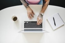 Elevated view of tattooed woman using laptop — Stock Photo