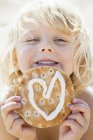 Young girl holding pastry with heart shaped icing — Stock Photo