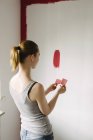 Visão traseira da mulher comparando amostras de cor contra a parede — Fotografia de Stock