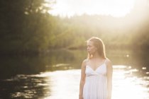 Mulher vestindo vestido branco por rio — Fotografia de Stock