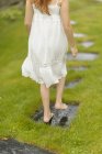 Girl in white dress walking down footpath — Stock Photo